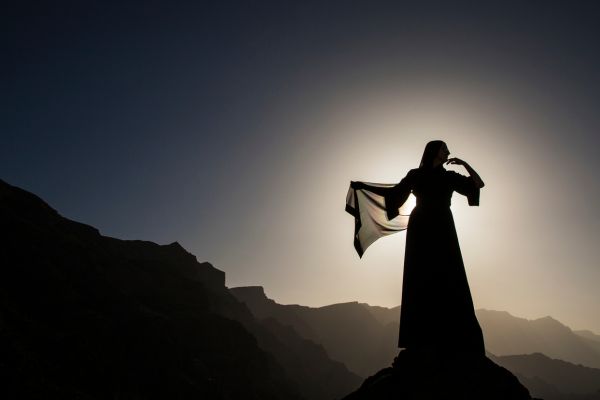 Muslim woman in abaya standing in a desert at dusk