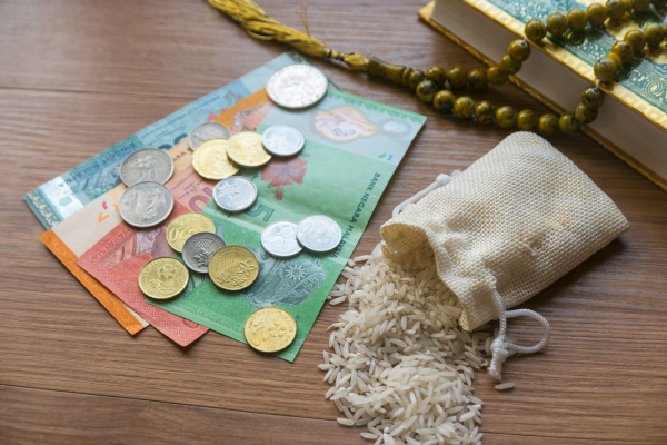 Monetary coins and bills next to a pouch of rice grains signifying zakat