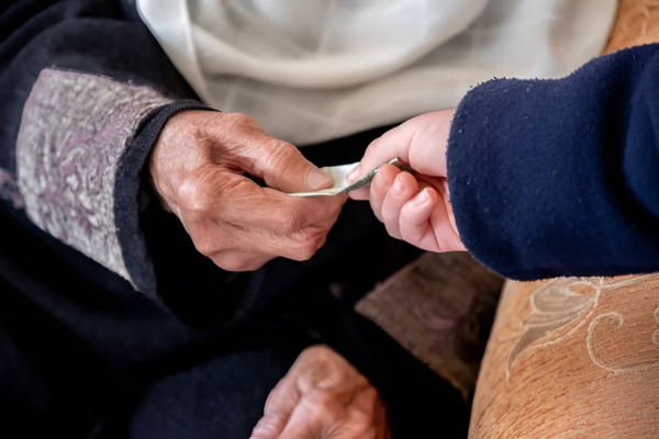 Muslim woman giving charity to an elder in the community