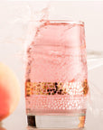 Transparent  glass dune tumbler with white and golden sands print filled with a pink color cold drink